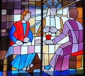 Das Glasfenster zeigt Jesus,wie er mit den Emmausjüngern das Brot teilt